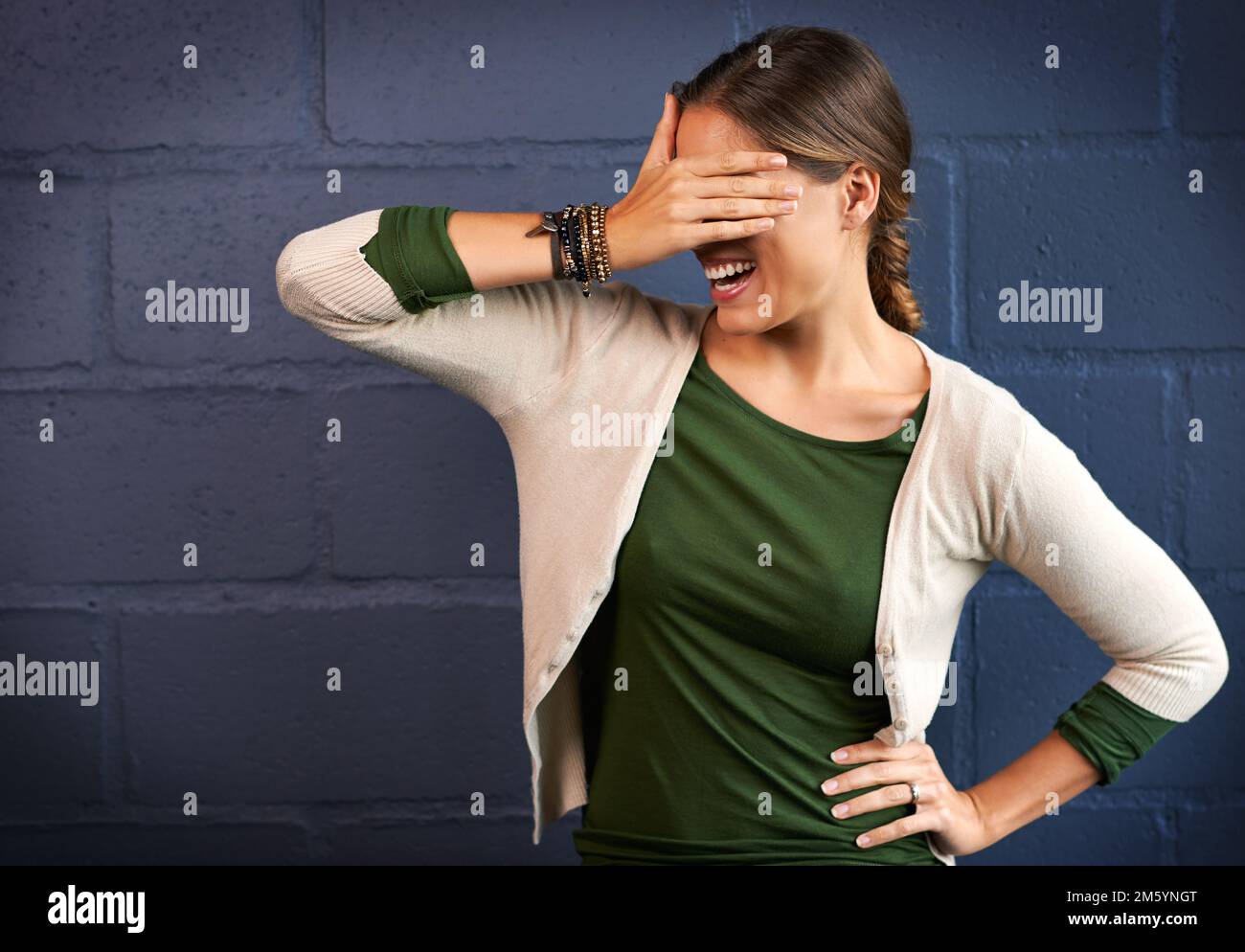 Qu'est-ce que je viens de voir. une jeune femme couvrant ses yeux contre un fond de mur de briques. Banque D'Images
