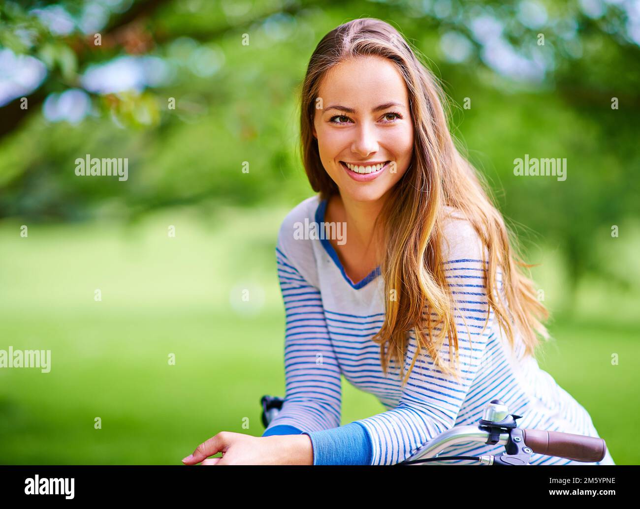 Belle journée pour être dehors. Portrait d'une jeune femme en vélo dans le parc. Banque D'Images