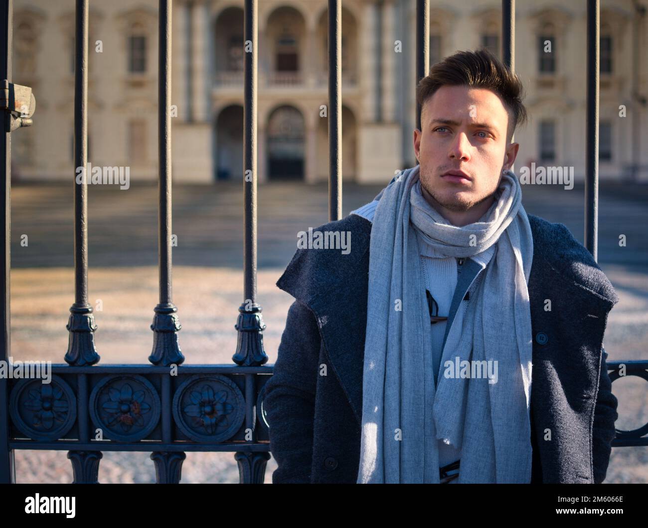 Un beau jeune homme en milieu urbain portant un manteau et une écharpe noirs en hiver Banque D'Images