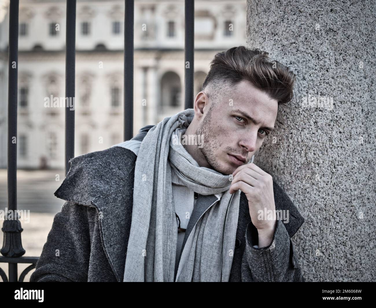 Un beau jeune homme en milieu urbain portant un manteau et une écharpe noirs en hiver Banque D'Images