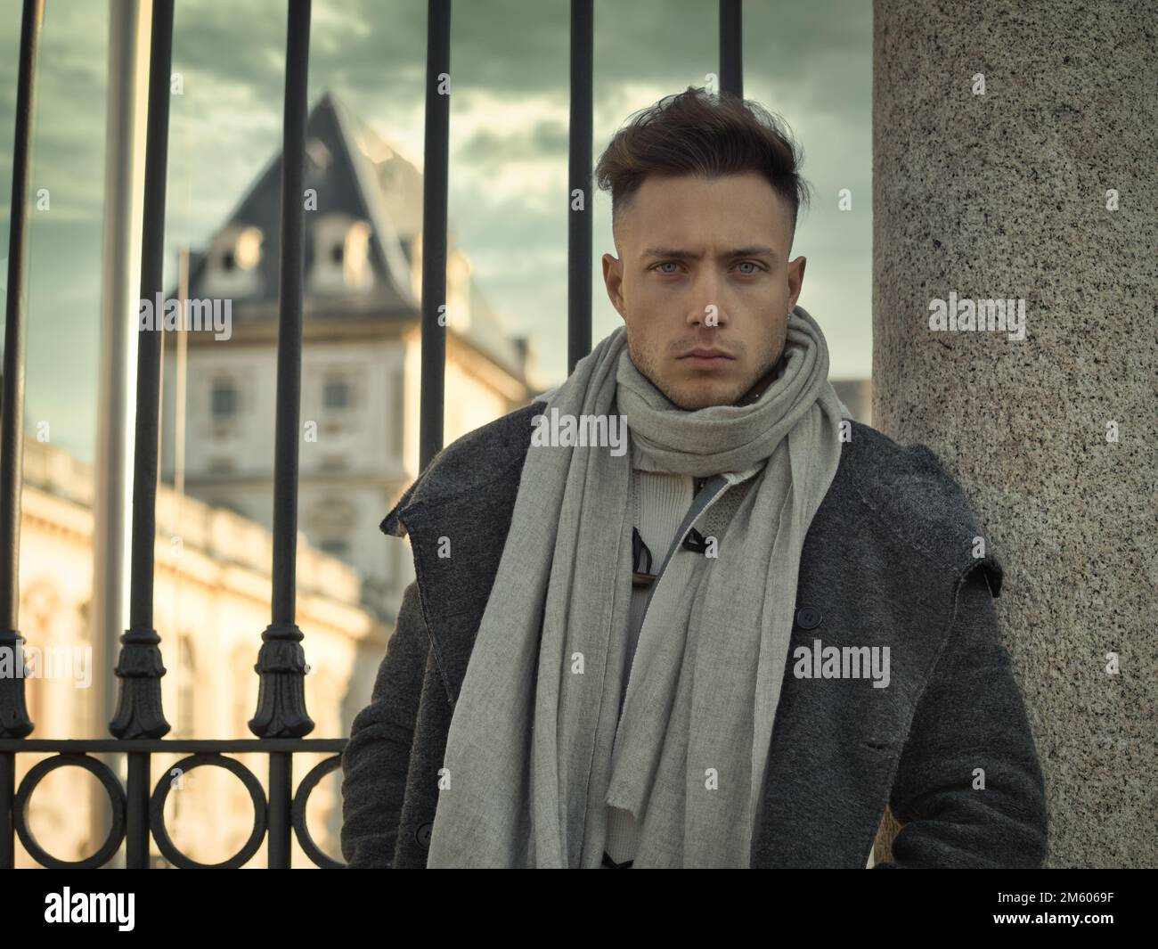 Un beau jeune homme en milieu urbain portant un manteau et une écharpe noirs en hiver Banque D'Images