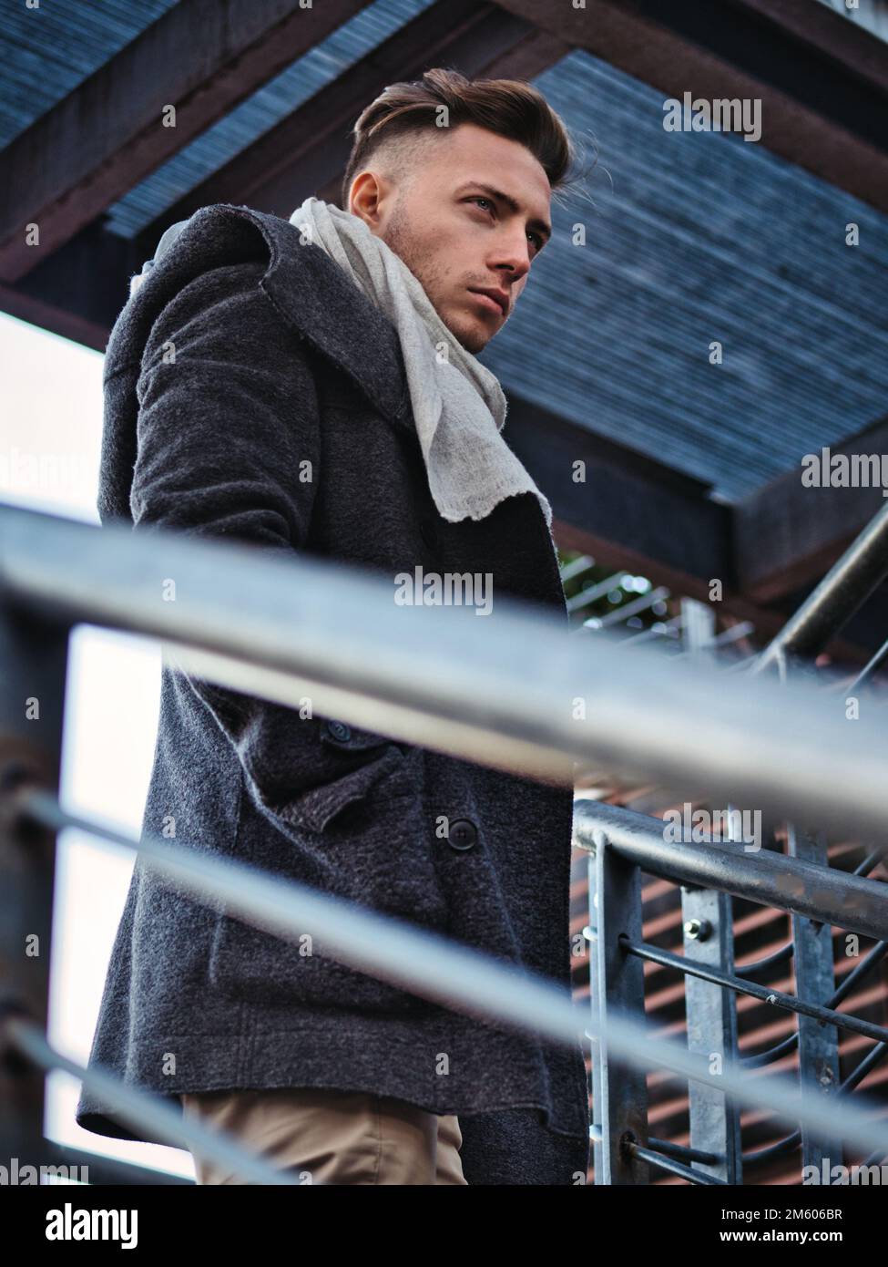 Un beau jeune homme en milieu urbain portant un manteau et une écharpe noirs en hiver Banque D'Images