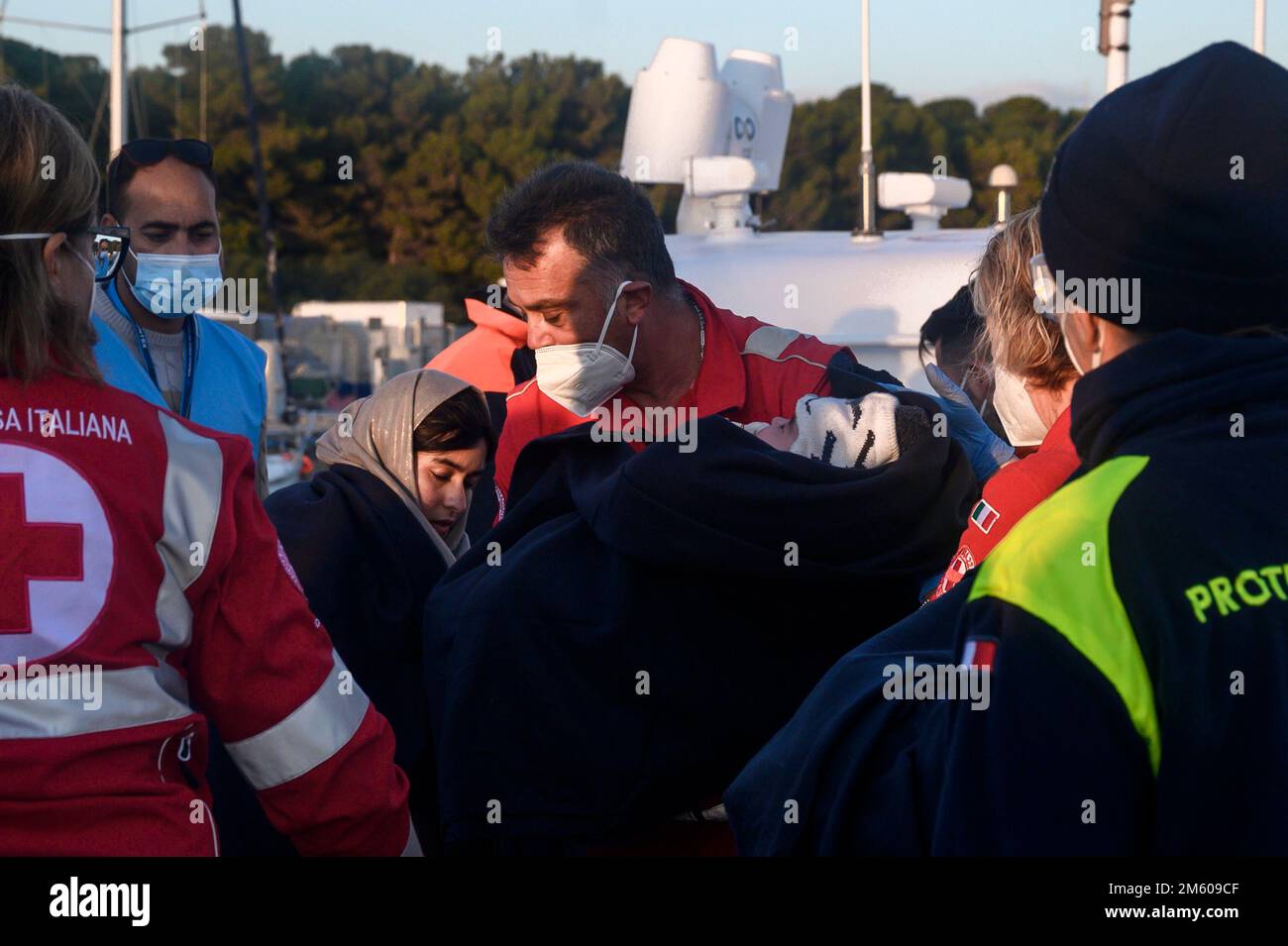 Roccella Jonica, Italie. 31st décembre 2022. Des membres de la Croix-Rouge vus prendre soin d'un enfant. Près de 90 migrants, principalement d'Afghanistan, du Pakistan et d'Iran, ont été sauvés par la Garde côtière italienne et emmenés au port de Roccella Jonica « Porto Delle Grazie ». Un bébé, né il y a trois jours pendant le passage à niveau, un nouveau-né de 11 jours et un bébé de cinq mois étaient également à bord. Des membres de la Croix-Rouge, des médecins sans frontières et du personnel sanitaire ont aidé les bébés, leurs familles et d'autres migrants. (Photo de Valeria Ferraro/SOPA Images/Sipa USA) crédit: SIPA USA/Alay Live News Banque D'Images