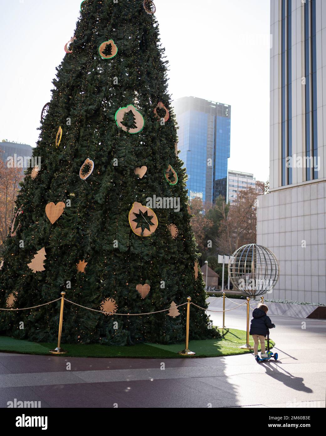 Petit enfant jouant avec un scooter autour de l'arbre de noël dans le centre de Madrid Banque D'Images