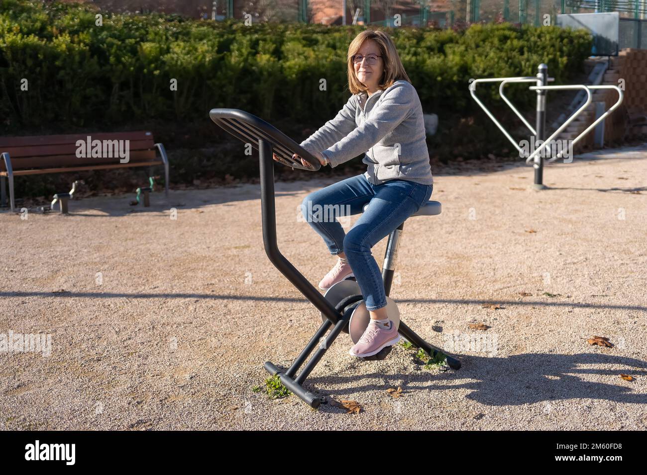 Femme senior à vélo d'appartement dans un parc public de la ville pour garder la forme. Banque D'Images