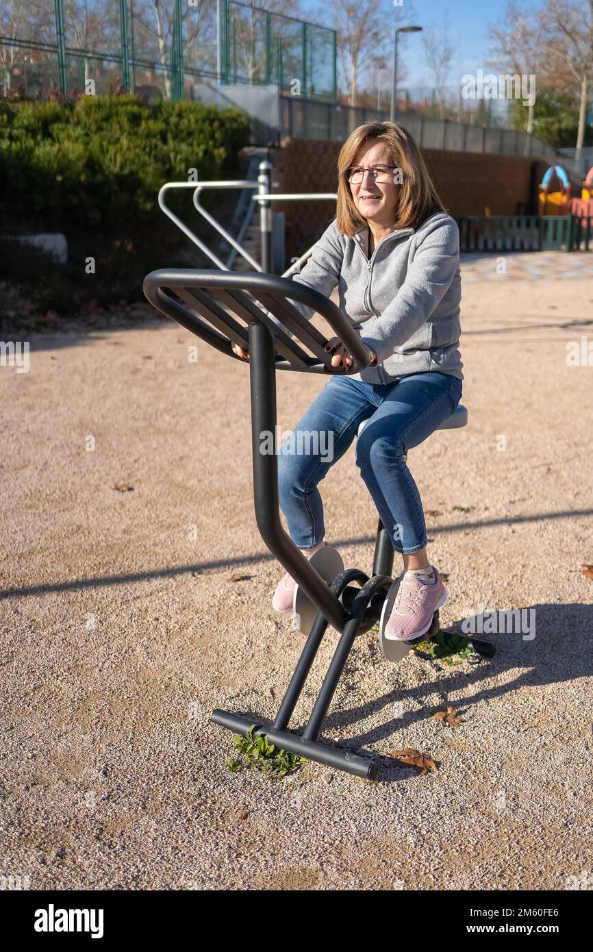 Femme senior à vélo d'appartement dans un parc public de la ville pour garder la forme. Banque D'Images