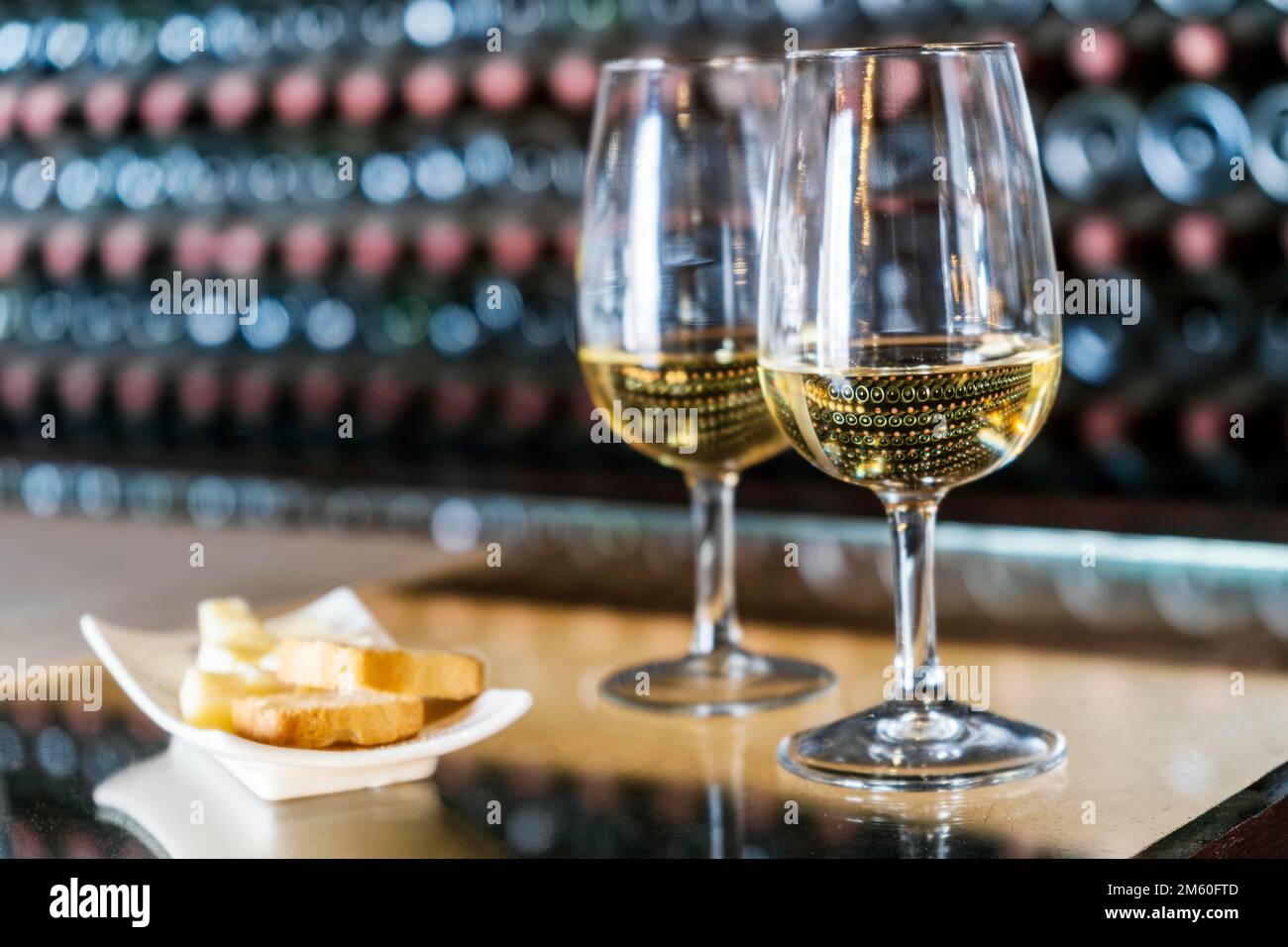 Dégustation de vins dans le domaine viticole, 2 verres de vin blanc avec toasts et fromage avec des centaines de bouteilles de vin empilées derrière, Lanzarote, Espagne Banque D'Images