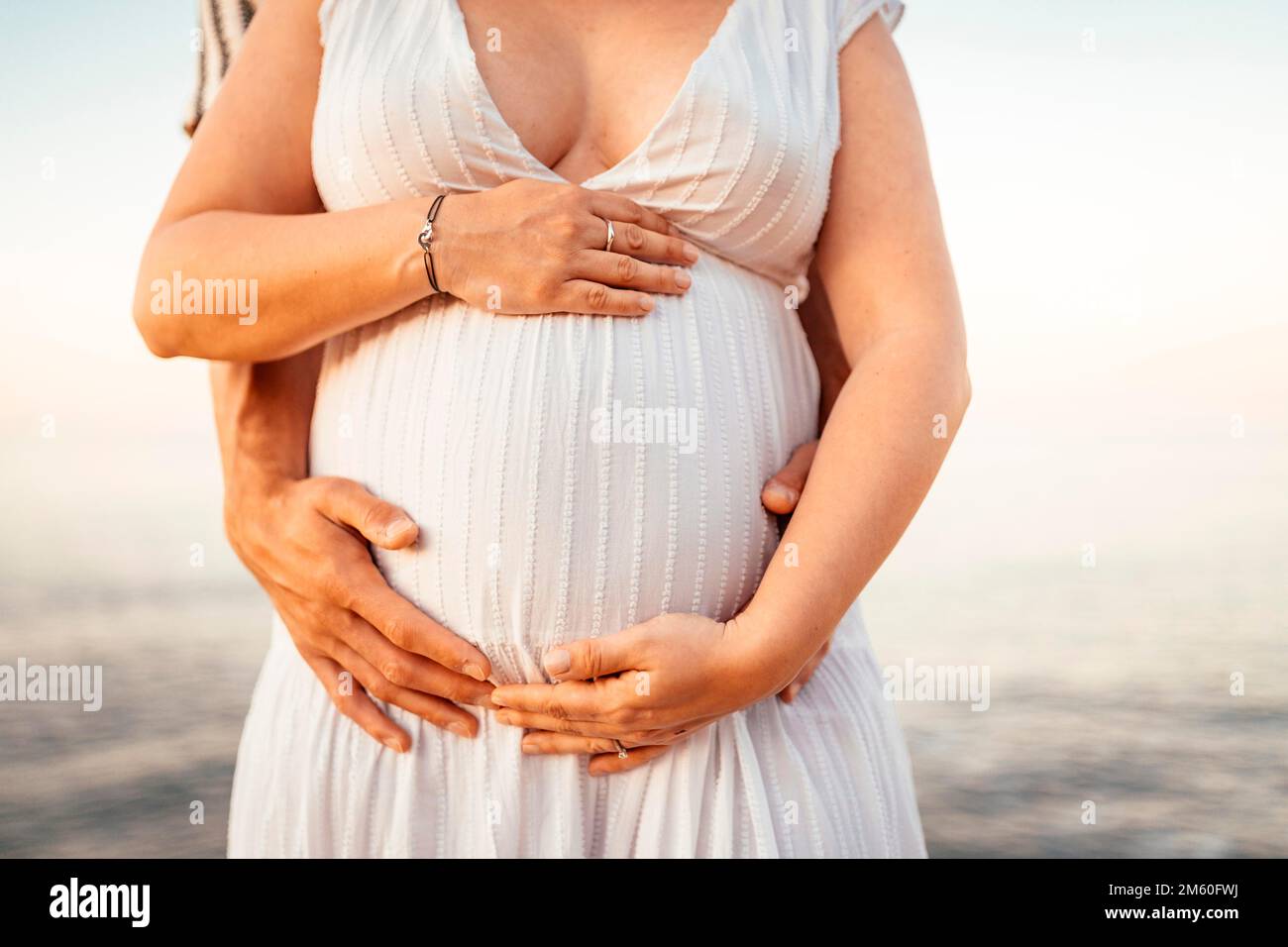 Femme enceinte avec son partenaire tenant son ventre dans la nature Banque D'Images