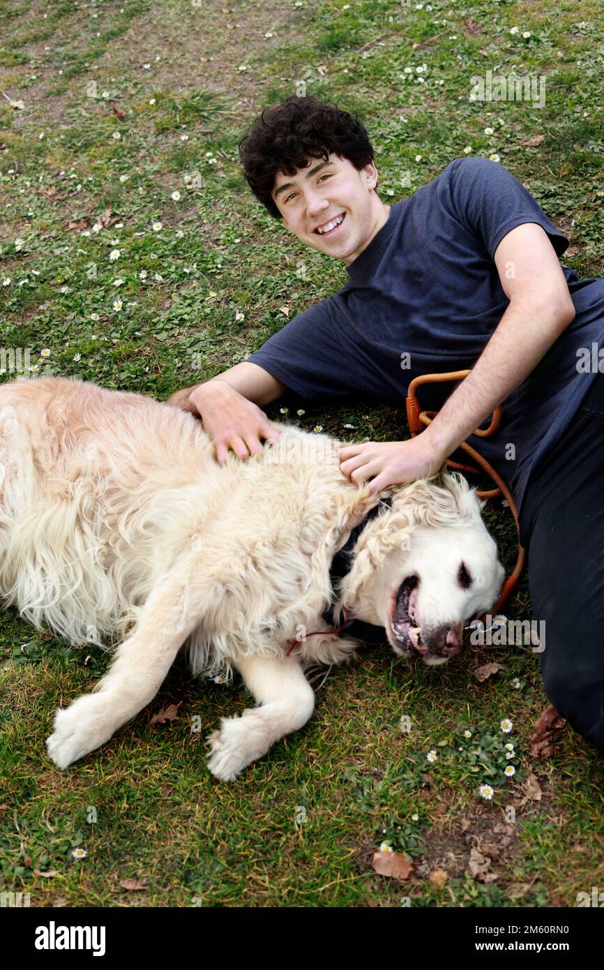 JOYEUX GARÇON AVEC SON CHIEN POSÉ SUR L'HERBE Banque D'Images