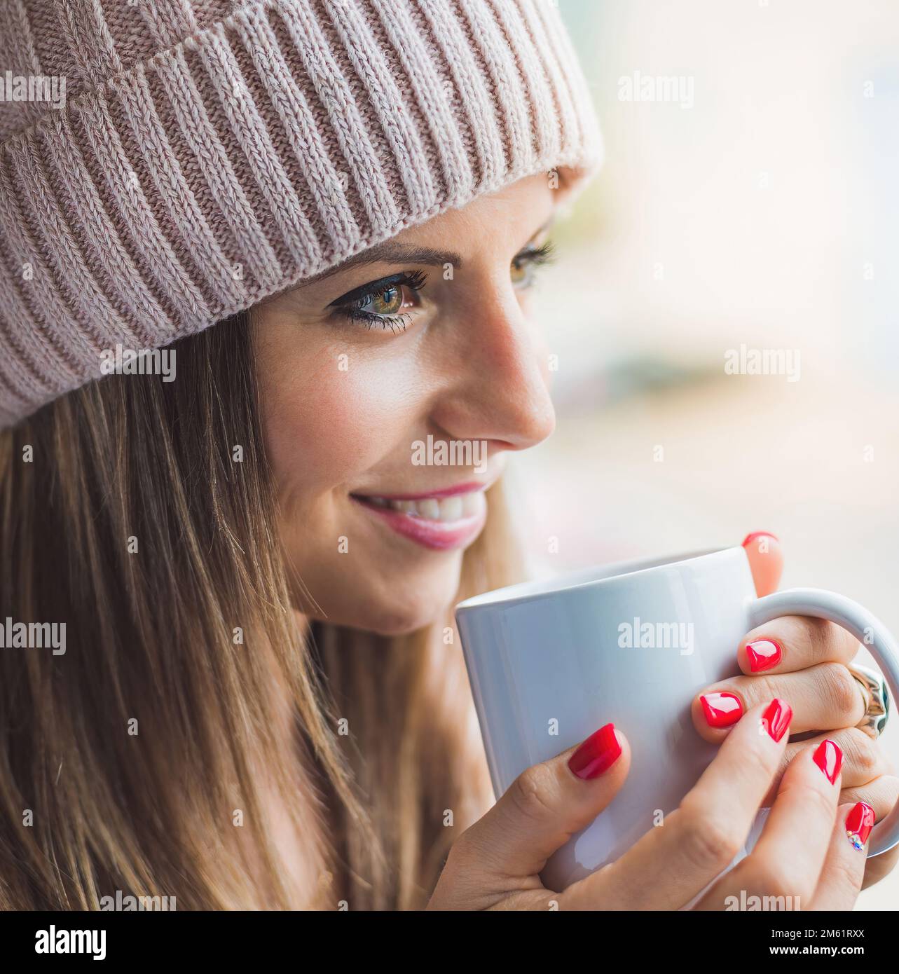 femme caucasienne avec capuchon en laine dans le profil tenant une tasse de café blanc. concept de détente et de bien-être. Banque D'Images