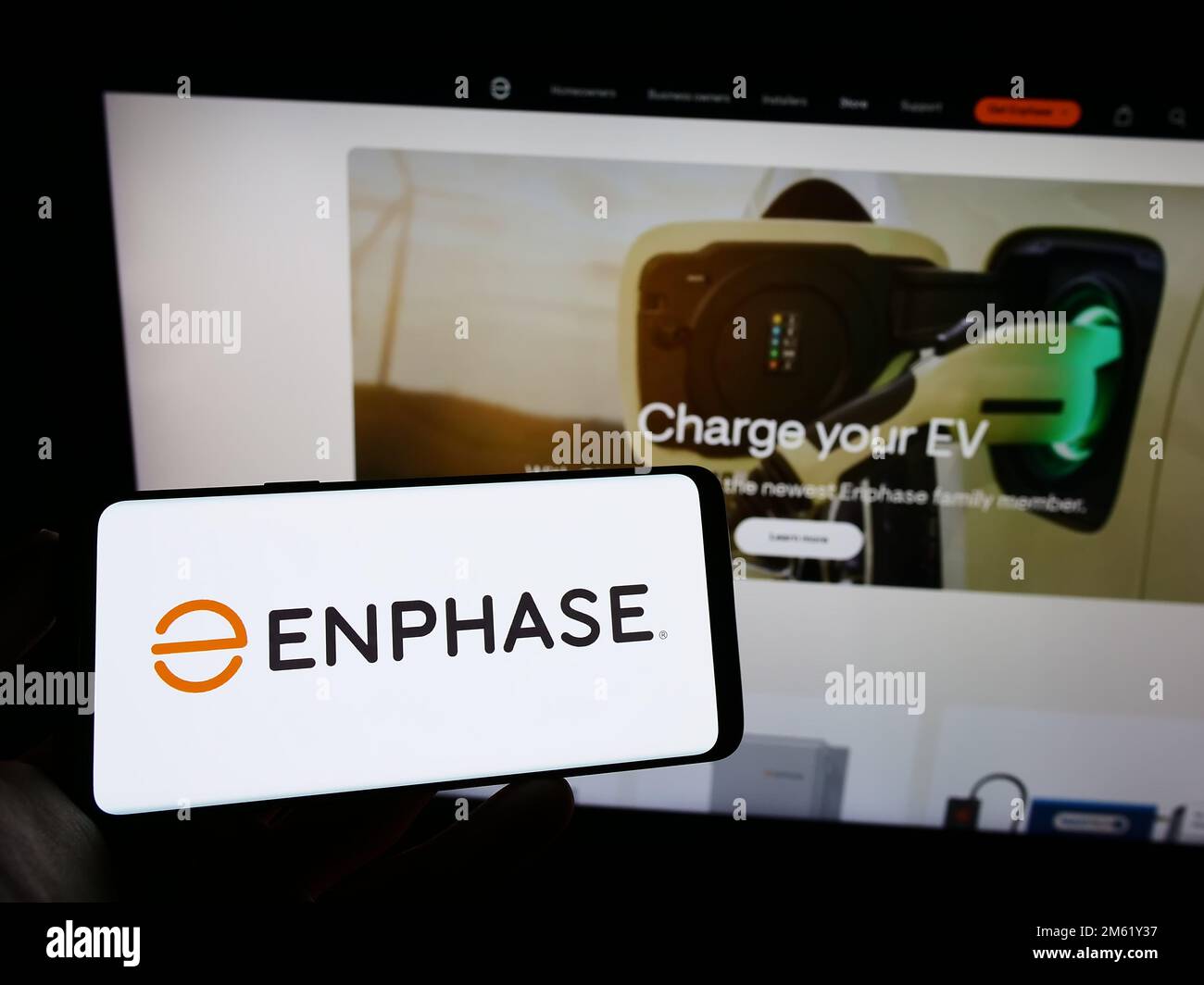 Personne tenant un téléphone portable avec le logo de la société américaine Enphase Energy Inc. À l'écran en face de la page Web d'affaires. Mise au point sur l'affichage du téléphone. Banque D'Images