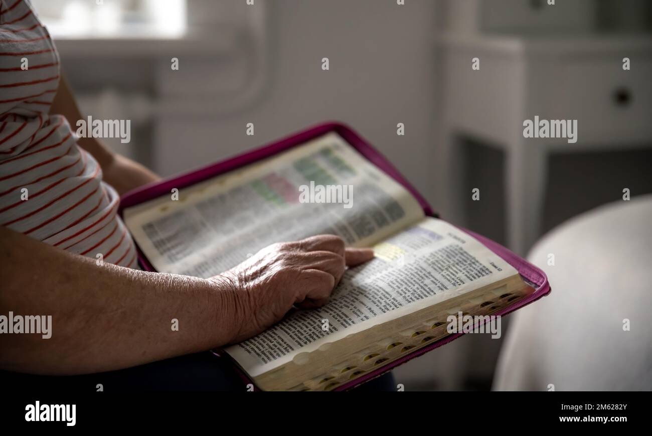 Une vieille femme lit la Bible, les mains de près. Banque D'Images