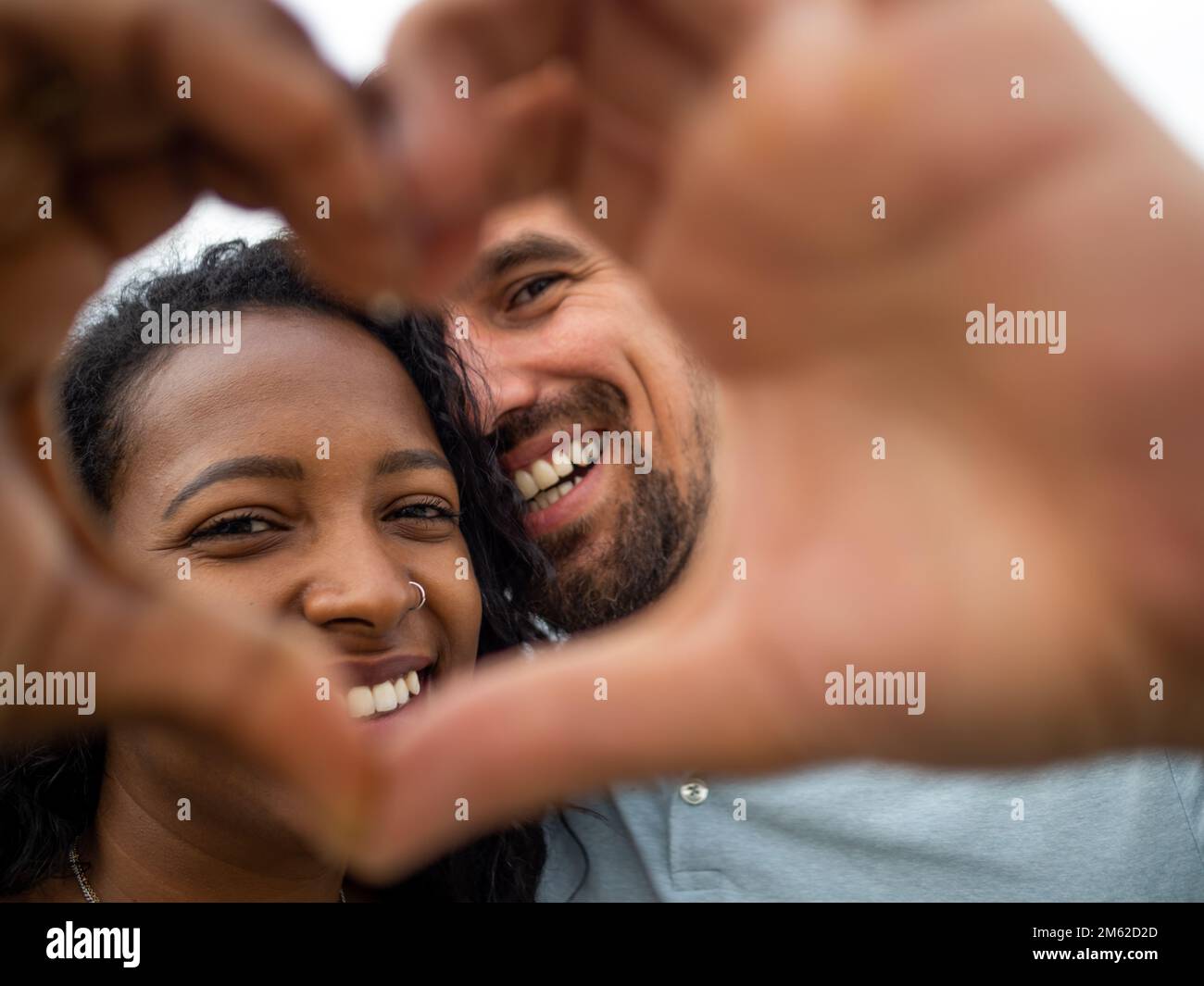 Jeune couple hétérosexuel souriant faisant un symbole de coeur avec leurs mains. Concept de lune de miel, jour de la Saint-Valentin Banque D'Images