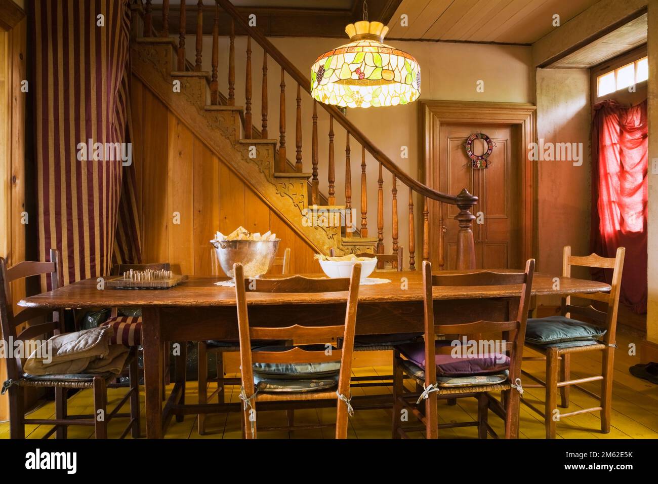Longue table à manger antique en bois teinté brun et chaises dans la salle à manger avec lampe tiffany à l'intérieur de la vieille maison en pierre de champ Canadiana 1838. Banque D'Images