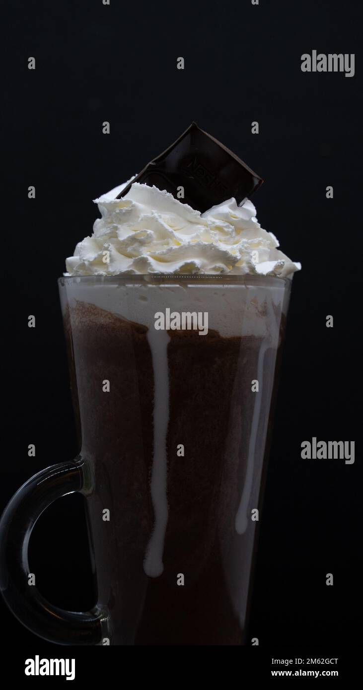 tasse de café avec crème fouettée et chocolat sur fond noir Banque D'Images