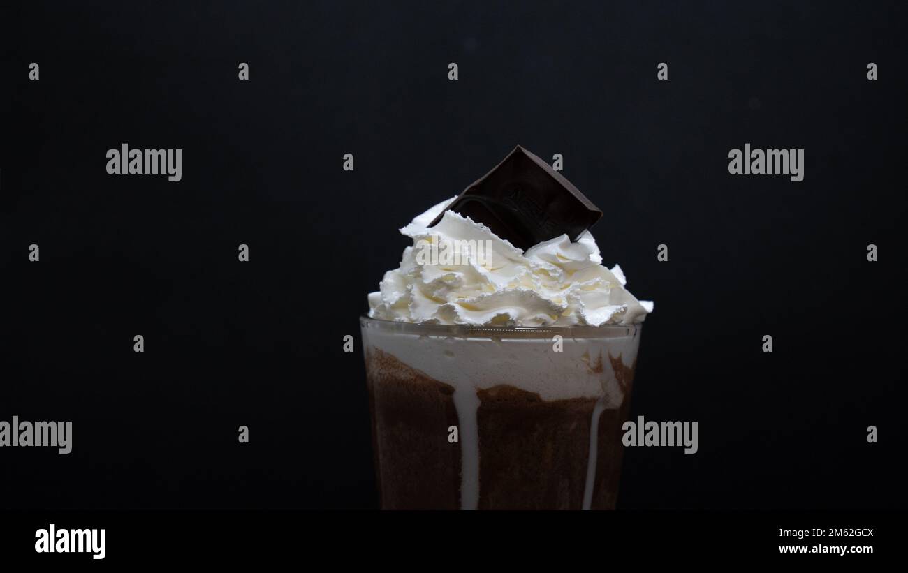 tasse de café avec crème fouettée et chocolat sur fond noir Banque D'Images