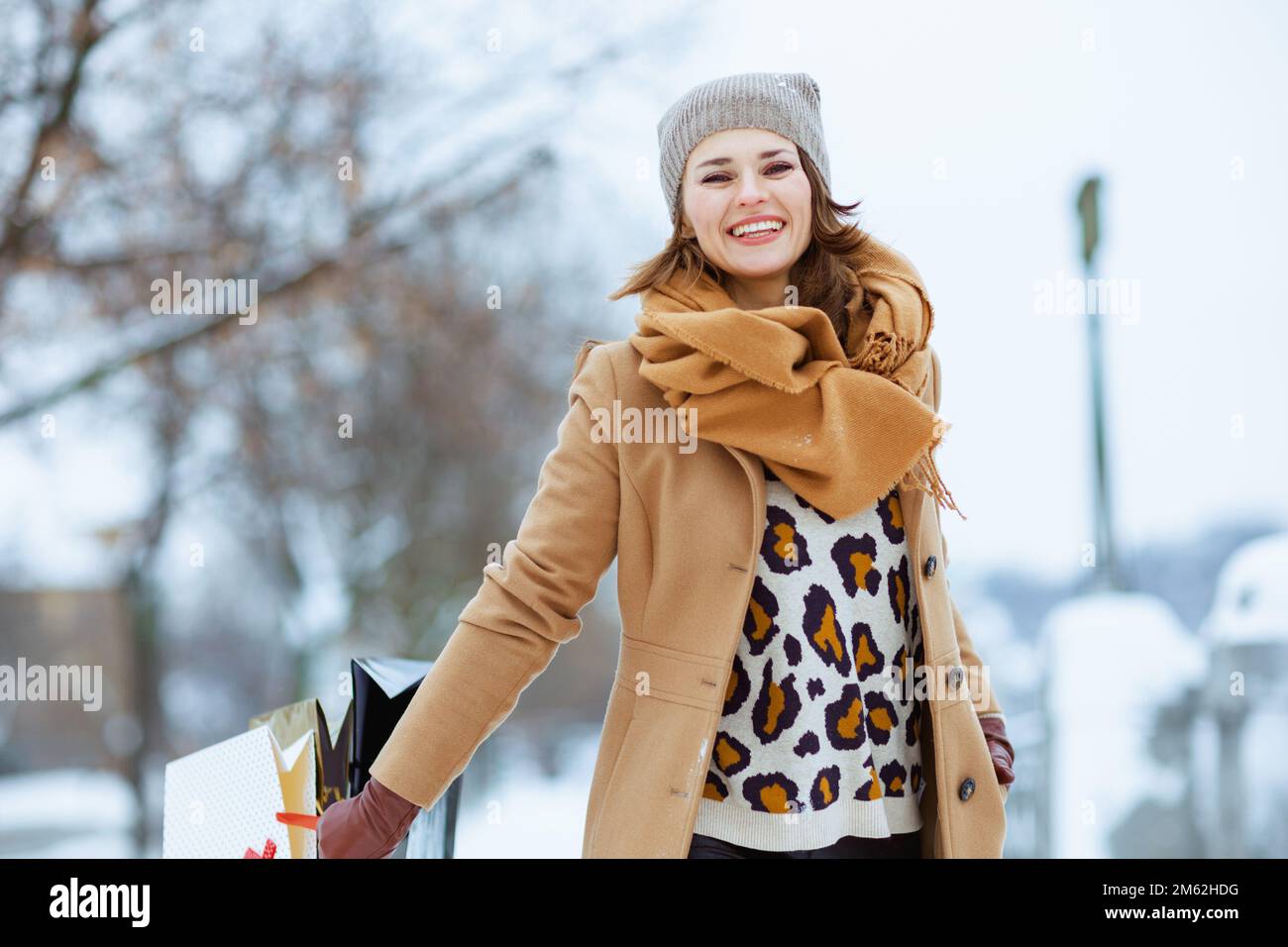bonne femme élégante en chapeau marron et écharpe en manteau de chameau  avec sacs de shopping à l'extérieur de la ville en hiver Photo Stock - Alamy
