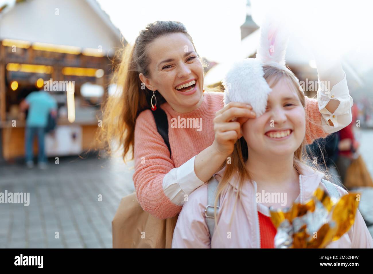 Pâques amusant. Portrait d'une jeune mère souriante et d'une fille adolescente avec un œuf de pâques doré à la foire de la ville. Banque D'Images