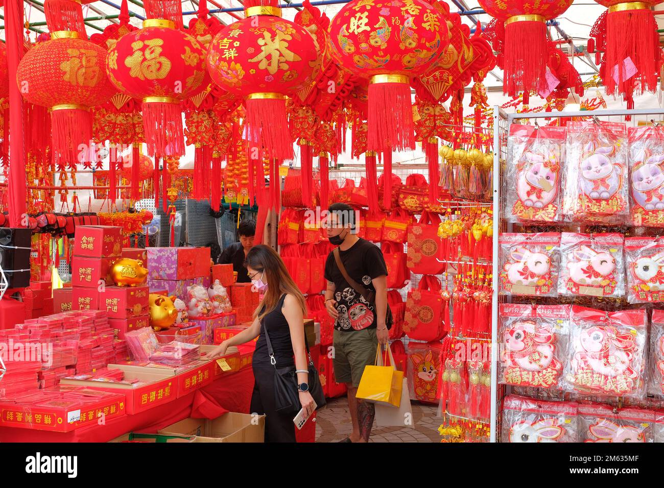 Les gens qui magasinent pour les ornements et les bibelots du nouvel an chinois dans une stalle rouge écarlate pour inaugurer l'année du lapin 2023 Banque D'Images