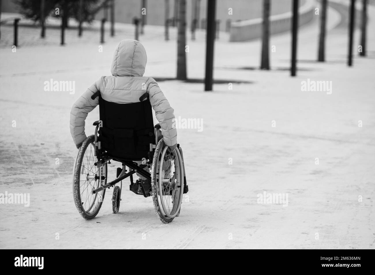 La femme sans domicile s'assoit en fauteuil roulant en hiver, en noir et blanc. Banque D'Images