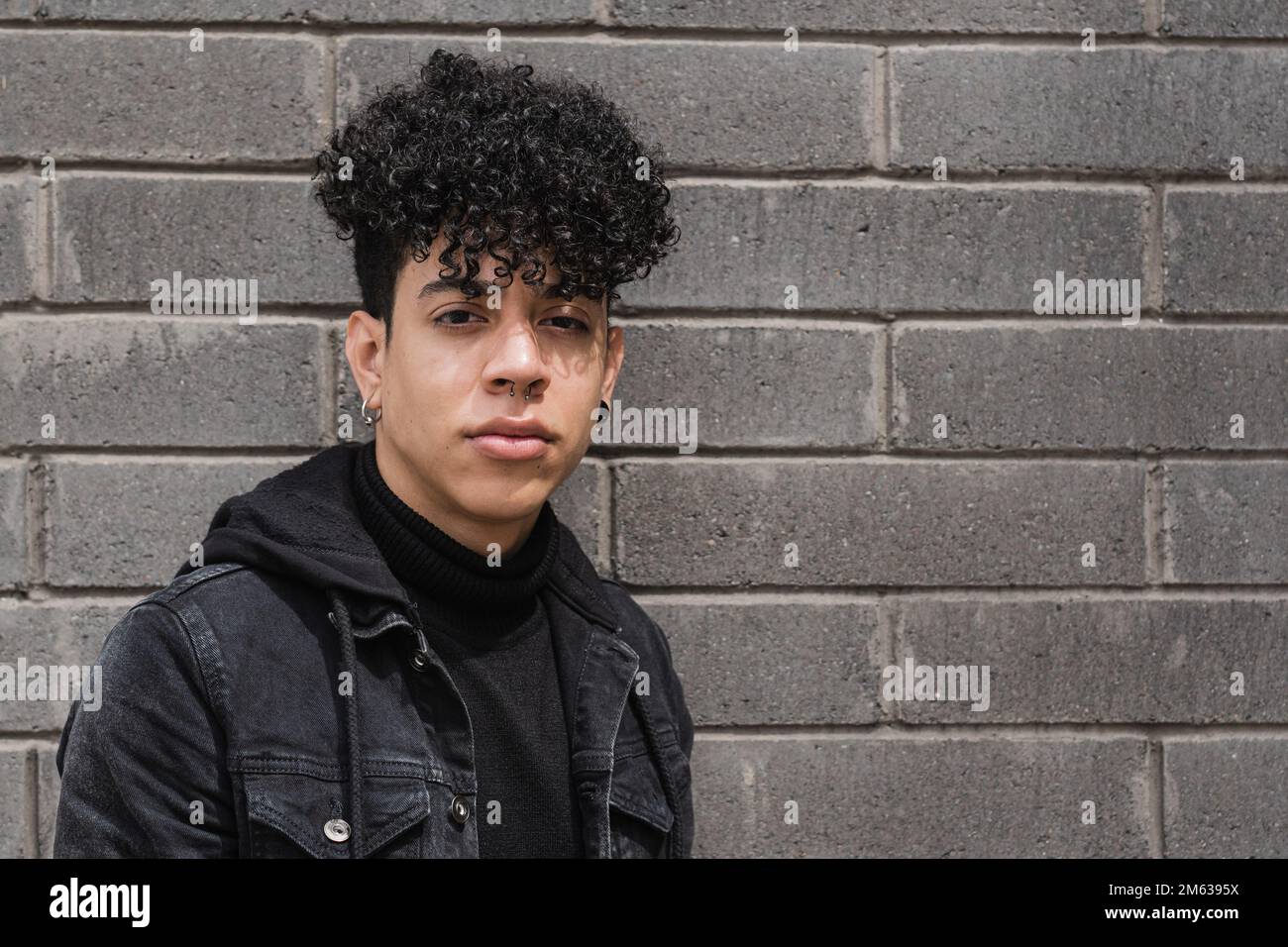 Portrait d'un jeune homme à poil dur ethnique dans une tenue décontractée debout regardant l'appareil photo Banque D'Images