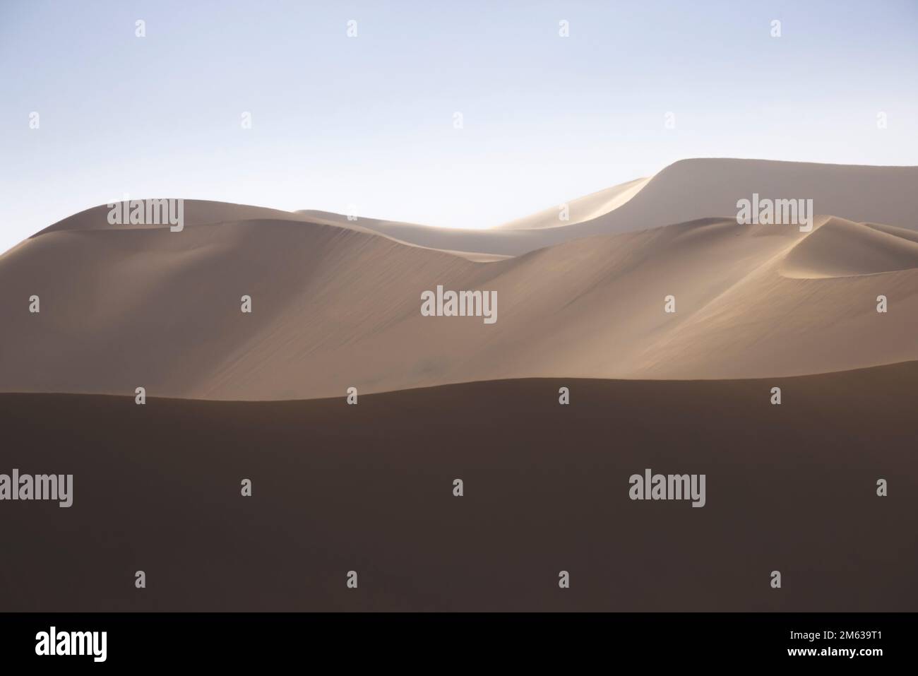 Paysage abstrait de magnifiques dunes de sable de terre désertique dans la lumière douce et chaude du soleil avec ciel clair Banque D'Images