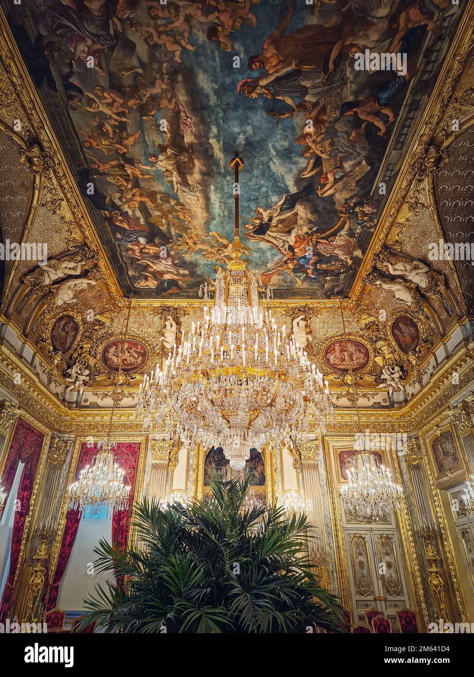 Beaux appartements Napoléon décorés au Palais du Louvre. Chambres familiales royales avec rideaux rouges cardinaux, murs dorés ornés, tableaux et cristal Banque D'Images