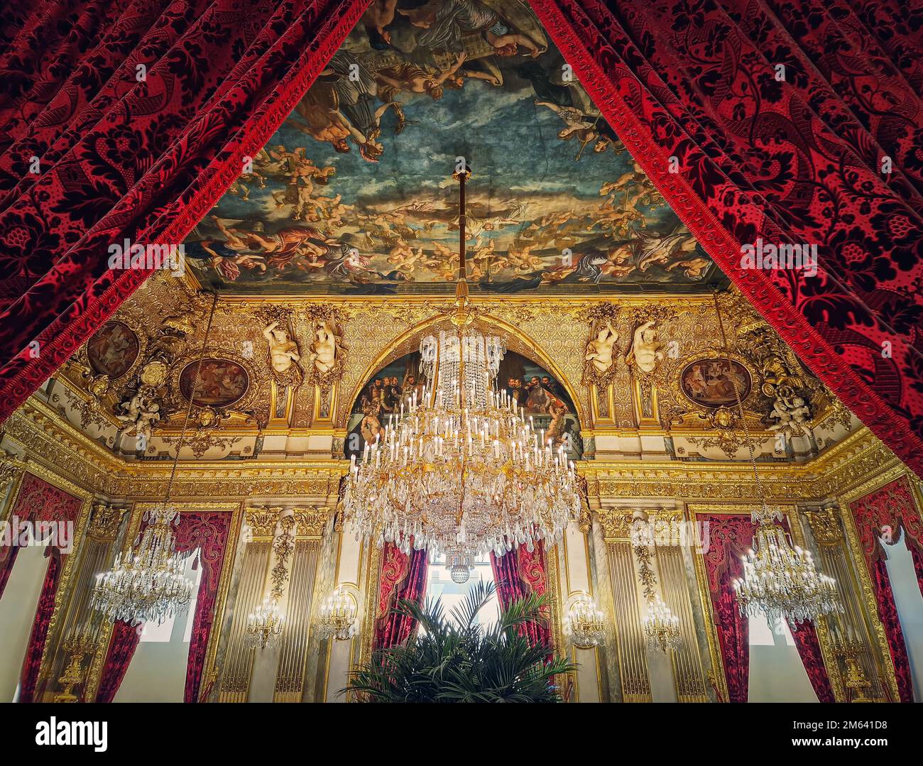 Beaux appartements Napoléon décorés au Palais du Louvre. Chambres familiales royales avec rideaux rouges cardinaux, murs dorés ornés, tableaux et cristal Banque D'Images