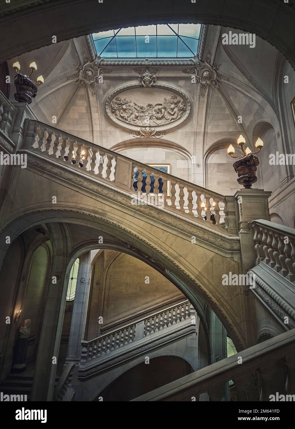 Palais du Louvre Détails architecturaux d'une salle avec escalier en pierre, balustrades ornées et lampes millésimes brillantes, Paris, France Banque D'Images