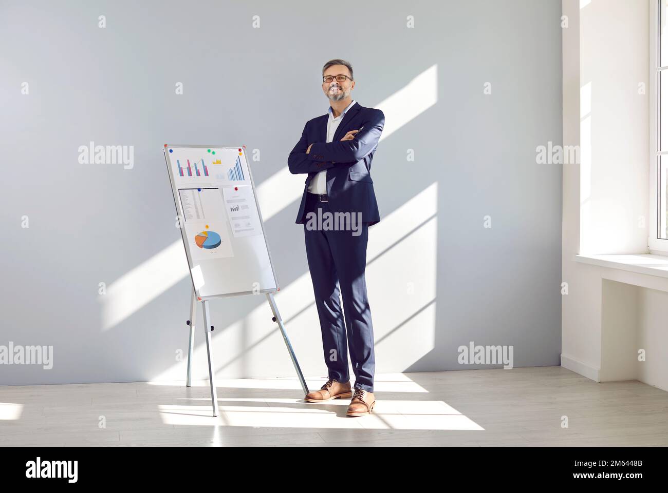Portrait d'un bon directeur des ventes mûr debout devant un tableau blanc de bureau Banque D'Images
