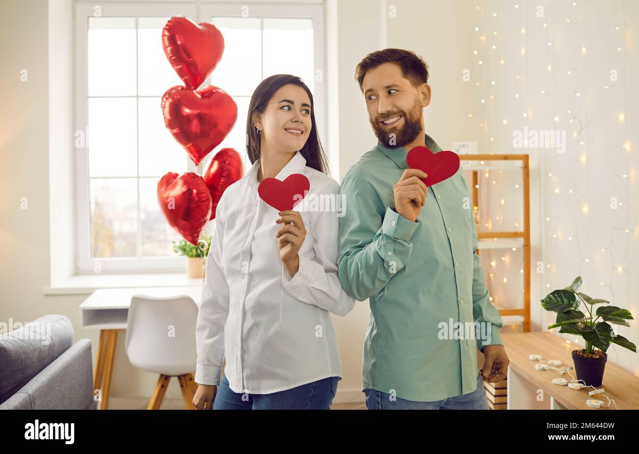Couple heureux tenant des coeurs en papier rouge regardant l'un l'autre Banque D'Images