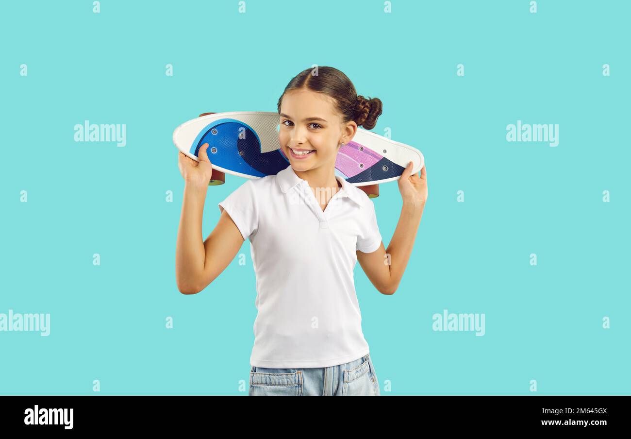 Heureuse belle fille en t-shirt blanc tenant son penny skateboard et souriant Banque D'Images