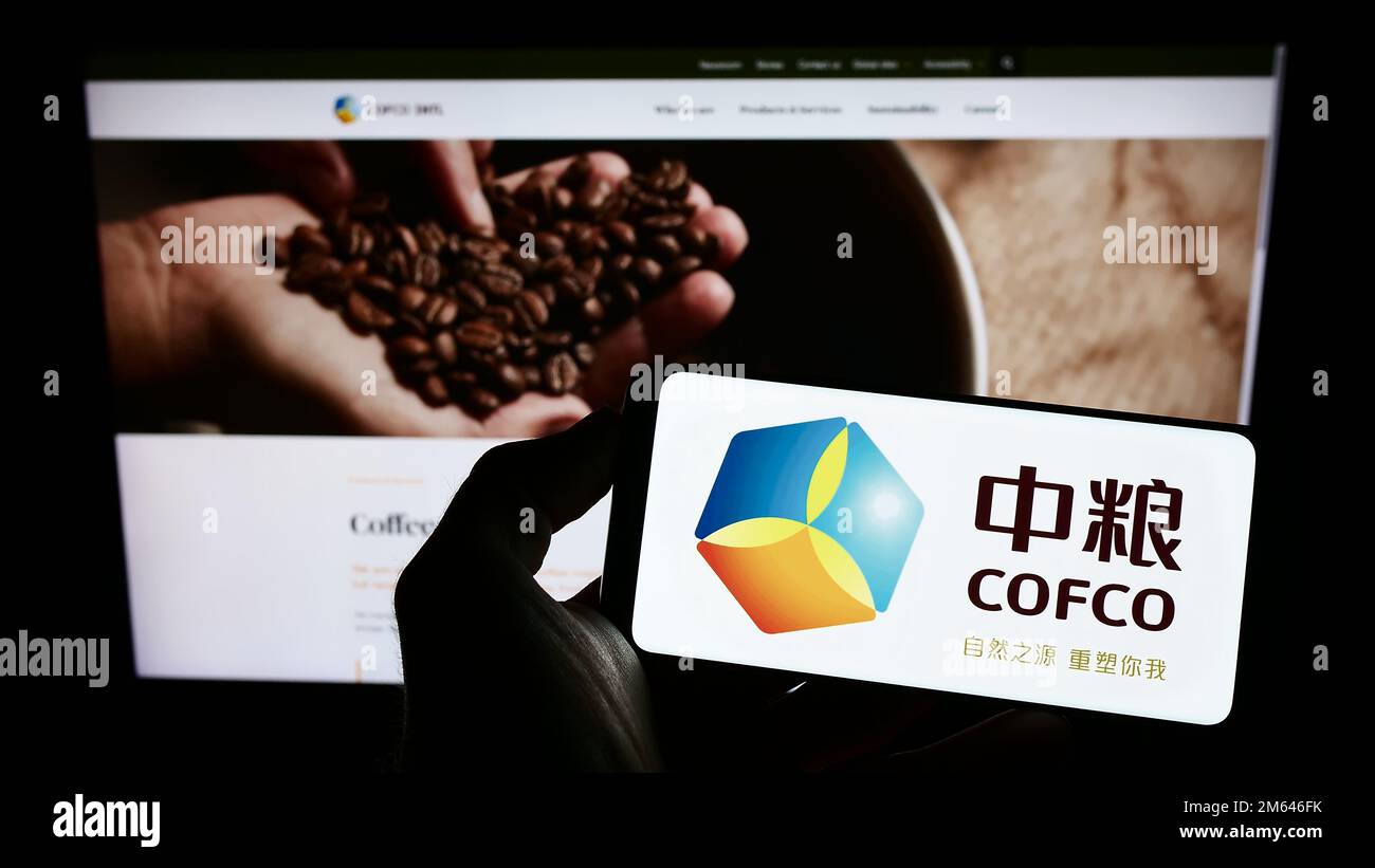 Personne tenant un téléphone portable avec le logo de China Oil and agro Corporation (COFCO) à l'écran devant la page Web. Mise au point sur l'affichage du téléphone. Banque D'Images