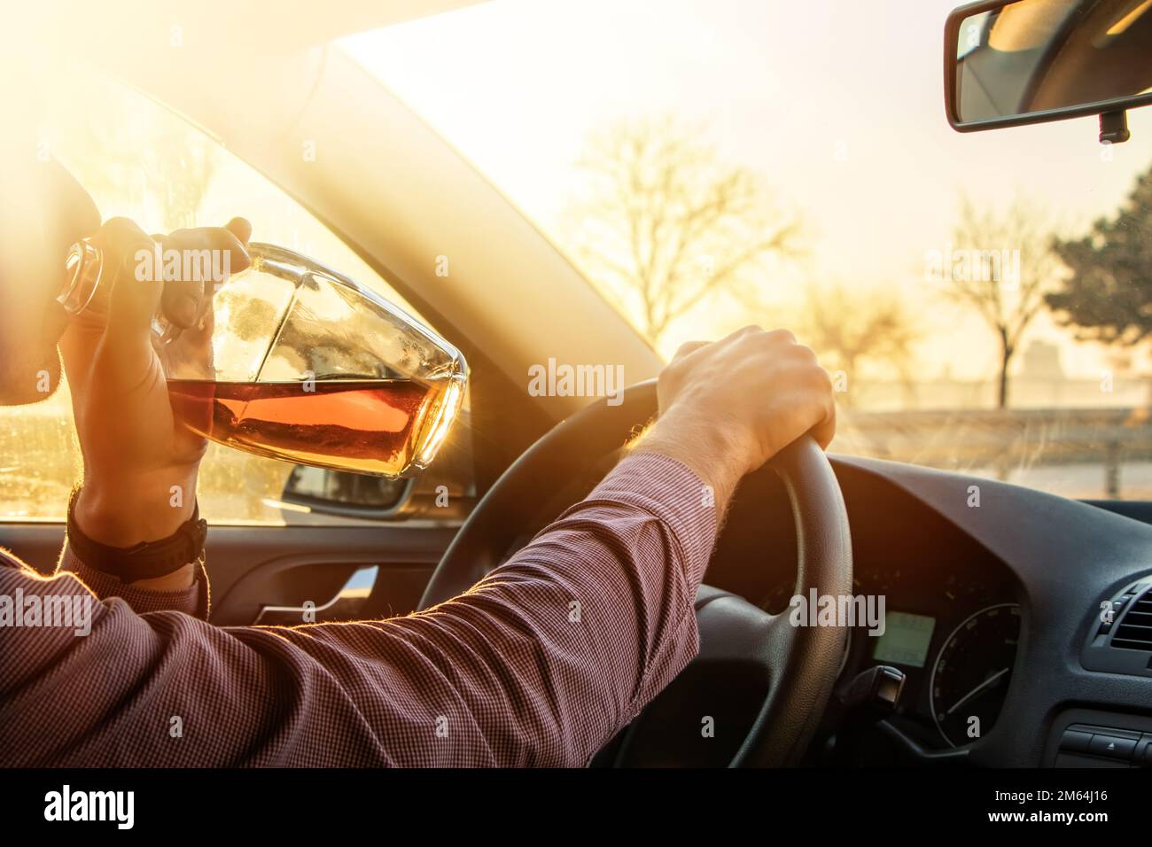 Homme qui boit de l'alcool en conduisant dans sa voiture au coucher du  soleil Photo Stock - Alamy