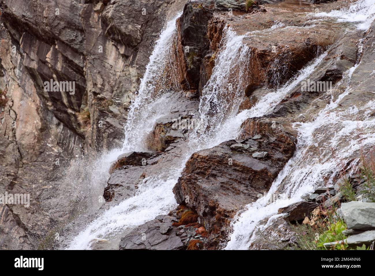 Belle texture de pierres de granit, peintes dans différentes nuances de brun: Du beige clair au noir presque noir, cascades d'eau coulant et moussant Banque D'Images