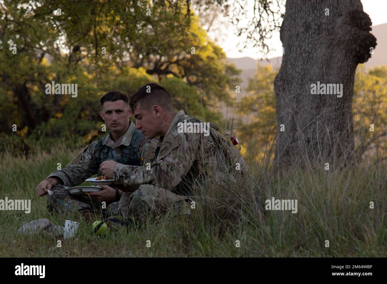 Le sergent d'état-major Mitchell Hinton et le SPC Austin Pogrebra, soldats représentant le Commandement des affaires civiles et des opérations psychologiques de l'armée des États-Unis (aéroporté), dînent sur le terrain après avoir terminé un cours de navigation terrestre d'une journée pendant la compétition combinée des meilleurs guerriers de 2022 à fort Hunter-Liggett, Californie, 1 avril. Cette année, 15 soldats ont voyagé pour participer au meilleur guerrier, organisé par USACAPOC(A), le Commandement de l'entraînement 84th et le Commandement de l'entraînement 108th (IET) de 31 mars à 5 avril 2022. Les concurrents sont évalués en fonction de leur capacité individuelle à s'adapter et à surmonter des scénarios difficiles et Banque D'Images