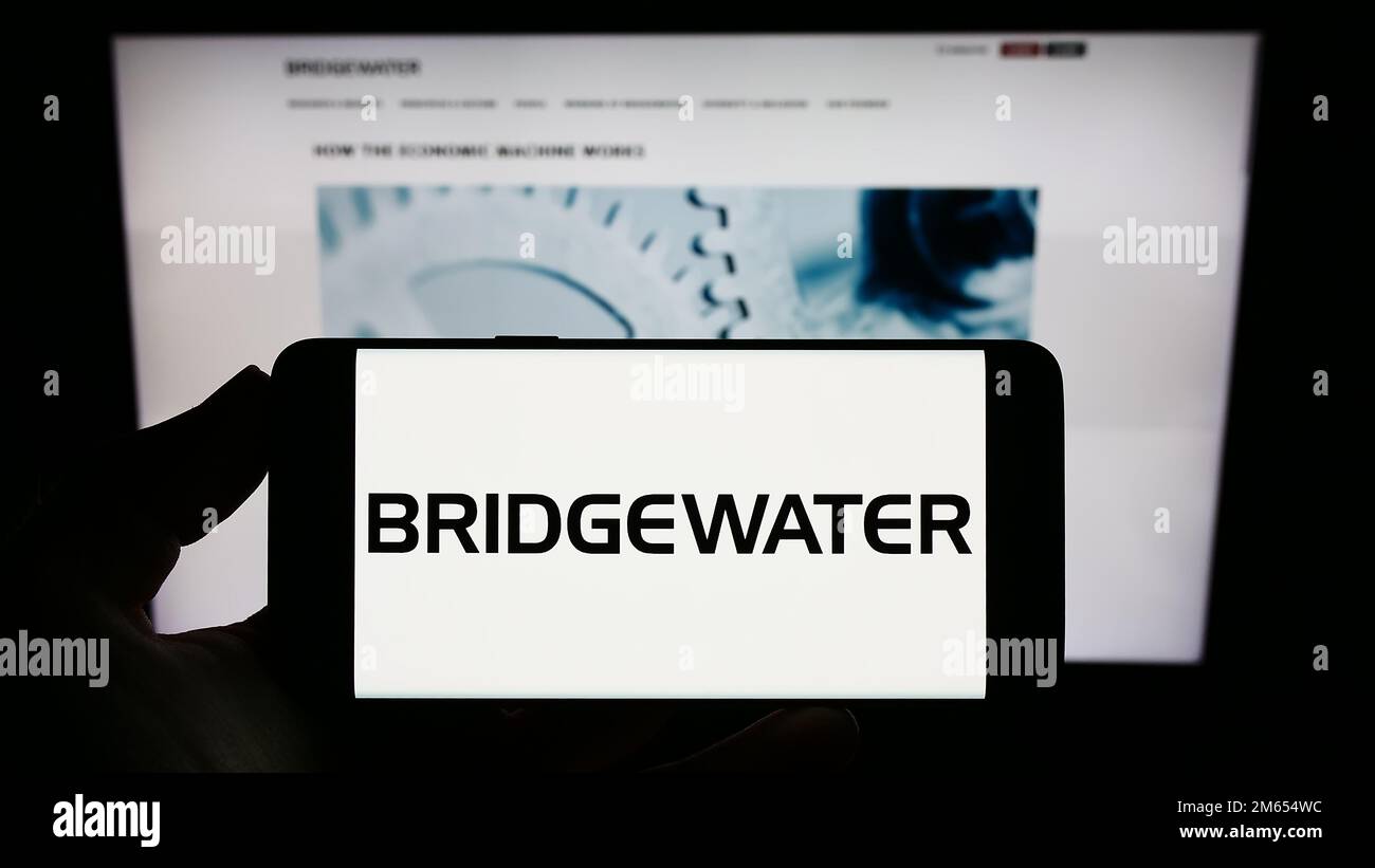 Personne détenant un smartphone avec le logo de la société d'investissement américaine Bridgewater Associates LP à l'écran devant le site Web. Mise au point sur l'affichage du téléphone. Banque D'Images