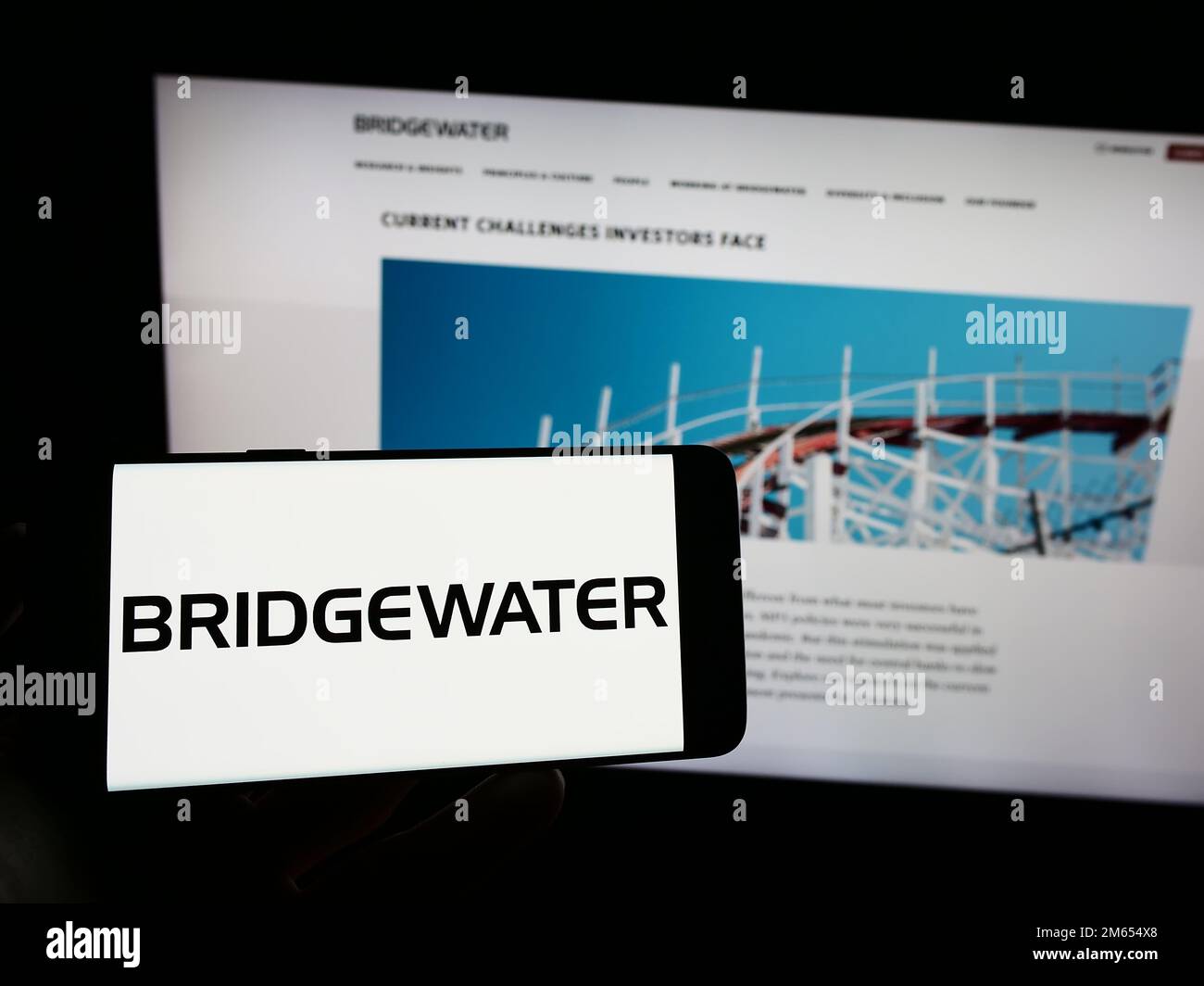 Personne tenant un téléphone cellulaire avec le logo de la société américaine d'investissement Bridgewater Associates LP à l'écran devant la page Web. Mise au point sur l'affichage du téléphone. Banque D'Images