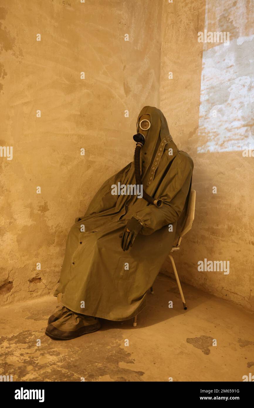 Figure assise dans des vêtements de protection comprenant un masque à gaz de la période de la Guerre froide, tel qu'exposé dans le musée Nowa Huta à Cracovie, en Pologne Banque D'Images