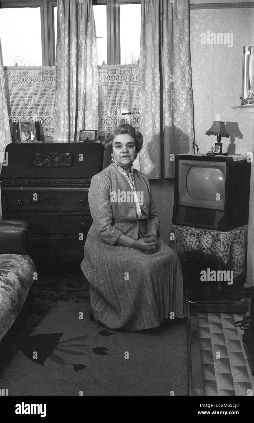 Fin 1950s, historique, une dame âgée dans un haut et longue jupe plissée, assis sur un tabouret dans sa chambre à côté de son téléviseur, Angleterre, Royaume-Uni. Les téléviseurs n'étaient pas un article de ménage courant dans cette époque, avec le moins cher disponible coûtant environ £ 80, ce qui serait environ £1 800 dans l'argent d'aujourd'hui. Banque D'Images Fin 1950s, historique, une dame âgée dans un haut et longue jupe plissée, assis sur un tabouret dans sa chambre à côté de son téléviseur, Angleterre, Royaume-Uni. Les téléviseurs n'étaient pas un article de ménage courant dans cette époque, avec le moins cher disponible coûtant environ £ 80, ce qui serait environ £1 800 dans l'argent d'aujourd'hui. Banque D'Images