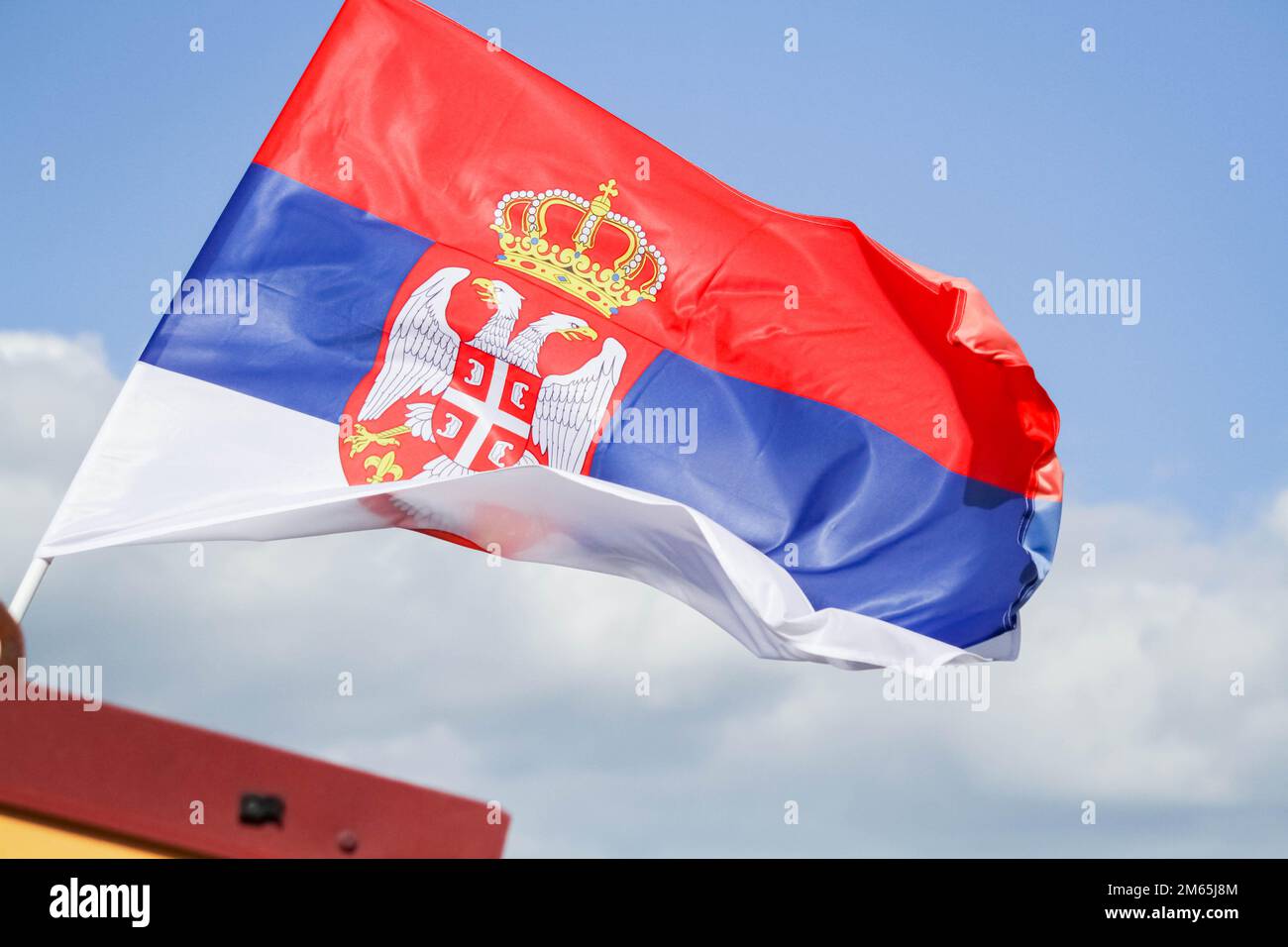 Le drapeau de la serbie contre le ciel bleu flotte dans le vent. Drapeau d'un pays en Europe. Banque D'Images