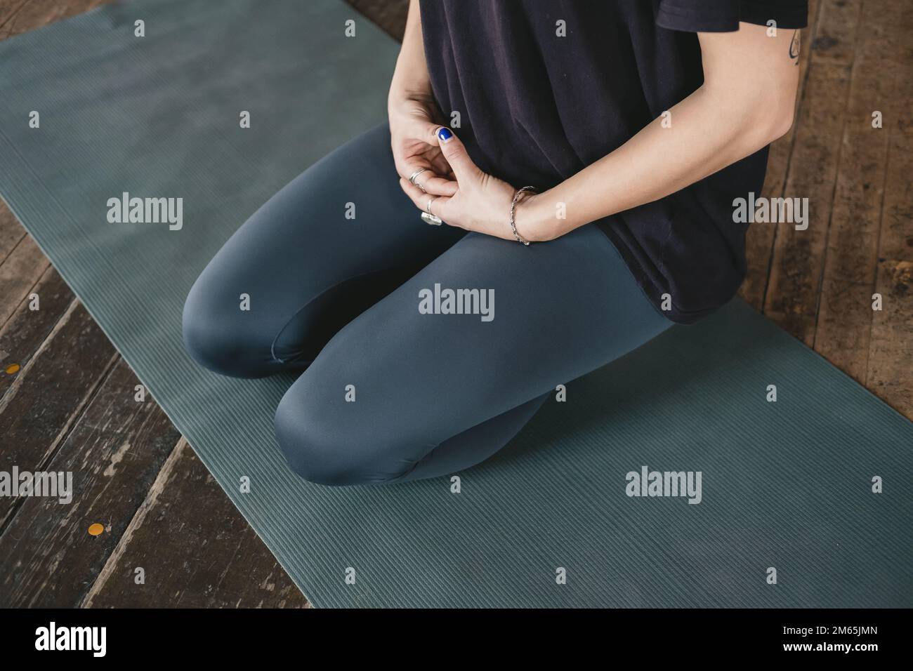 Photo en gros plan du tronc inférieur du corps d'une femelle yogi méditant dans la posture à genoux (vajrasana) lors de sa pratique de yoga de flux de vinyasa seul Banque D'Images
