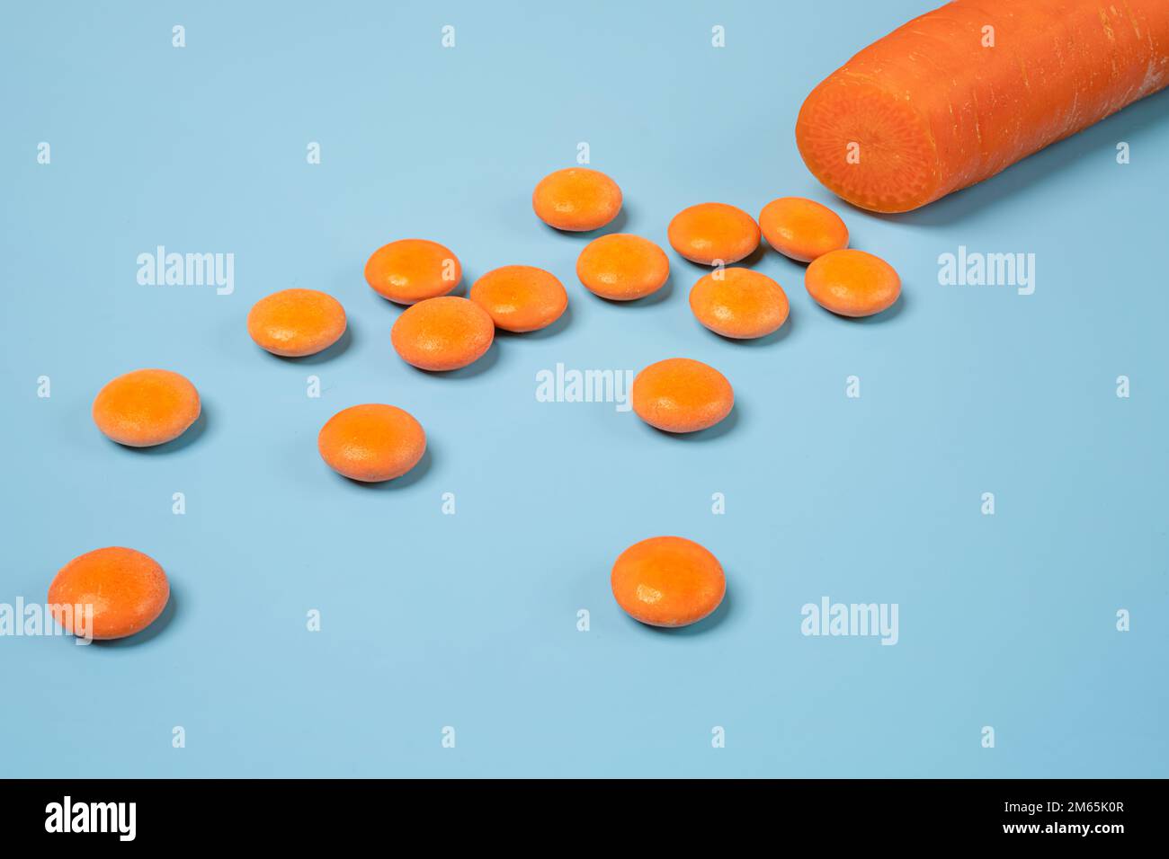 Une carotte coupée en dés et quelques comprimés de vitamine D orange Banque D'Images