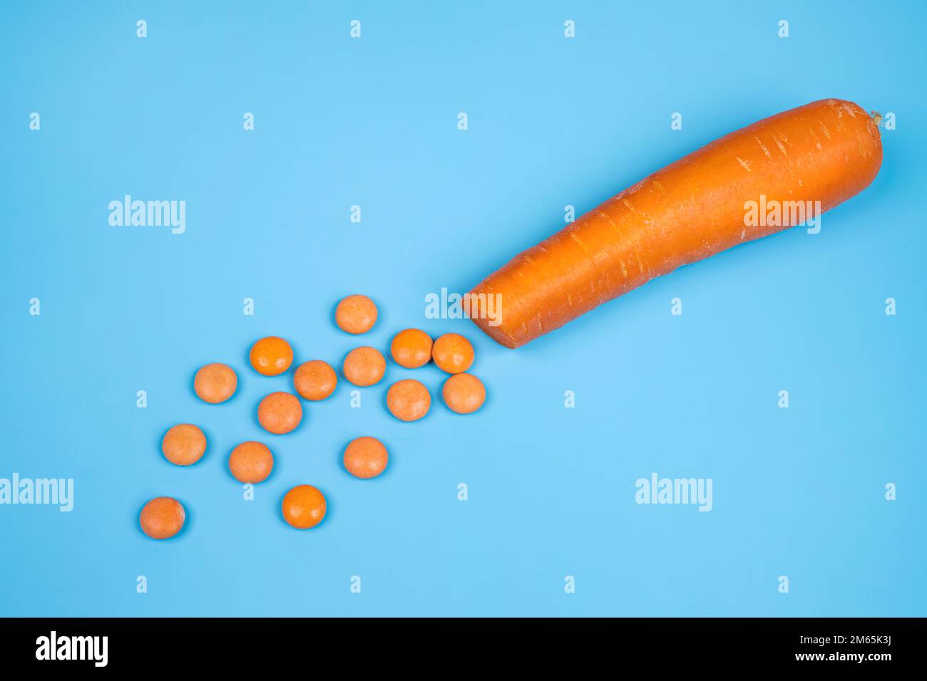 Une carotte coupée en dés et quelques comprimés de vitamine D orange Banque D'Images