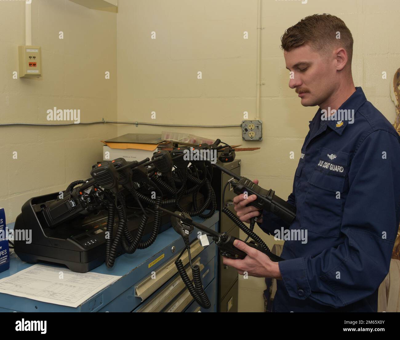 ÉTATS-UNIS Gardien de la côte le maître de classe 1st Mason Cambridge, et le technicien en électronique affecté temporairement au détachement de soutien de l'électronique Mayport, Floride, terminent la programmation et le codage des radios VHF portatives sécurisées au secteur de la Garde côtière Jacksonville, Floride, 5 avril 2022. Les radios permettent aux unités en visite d'établir rapidement des communications sécurisées avec le personnel du secteur Jacksonville et des unités subalternes. Banque D'Images