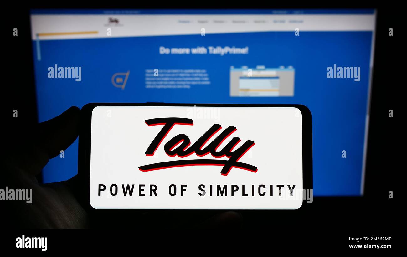 Personne tenant un smartphone avec le logo de la société de logiciel Tally Solutions Pvt. Ltd. Sur l'écran devant le site Web. Mise au point sur l'affichage du téléphone. Banque D'Images