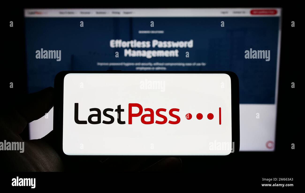 Personne tenant un téléphone portable avec le logo de la société de gestion de mot de passe LastPass US LP à l'écran en face de la page Web d'affaires. Mise au point sur l'affichage du téléphone. Banque D'Images