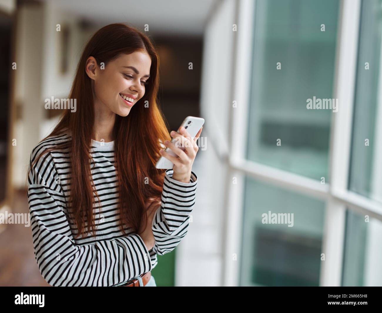 Femme souriant avec des dents regardant l'écran du téléphone dans ses mains heureux, chat vidéo en ligne appel, le concept de la technologie dans les réseaux sociaux Banque D'Images