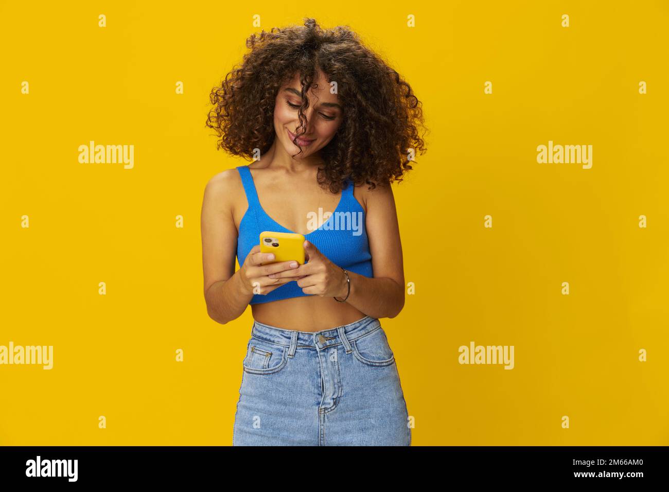 Influenceur femme avec le téléphone en main prenant des selfies parlant sur appel vidéo freelance travail de la technologie des médias sociaux, avec des cheveux frino maurly en chemise bleue Banque D'Images