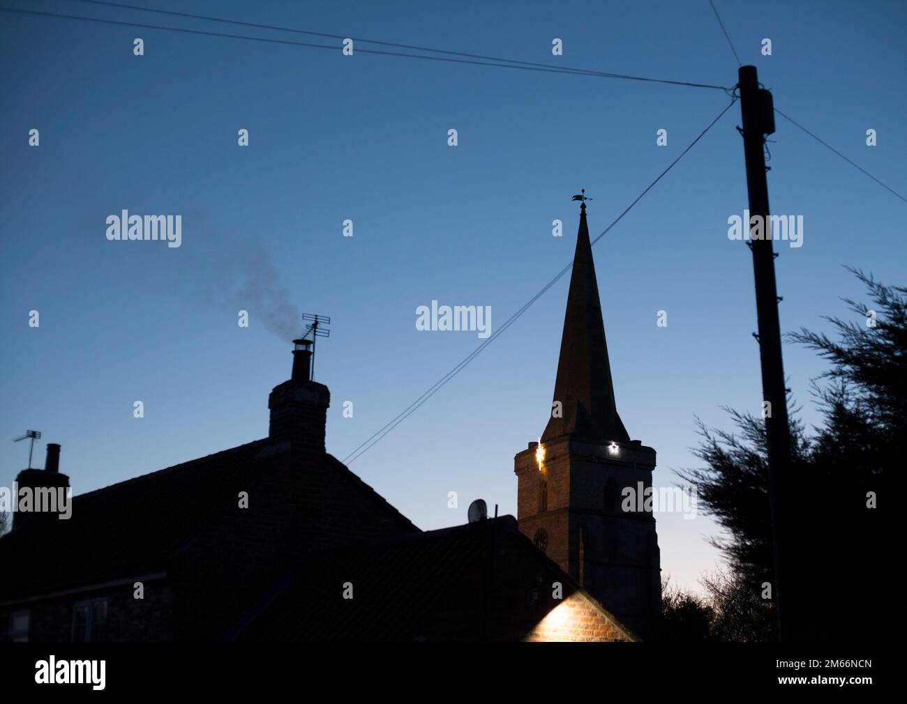 Noël festif lumières sur la campagne église village rural Ottringham Holderness East Riding of Yorkshire England UK prises au coucher du soleil avec un ciel bleu profond Banque D'Images